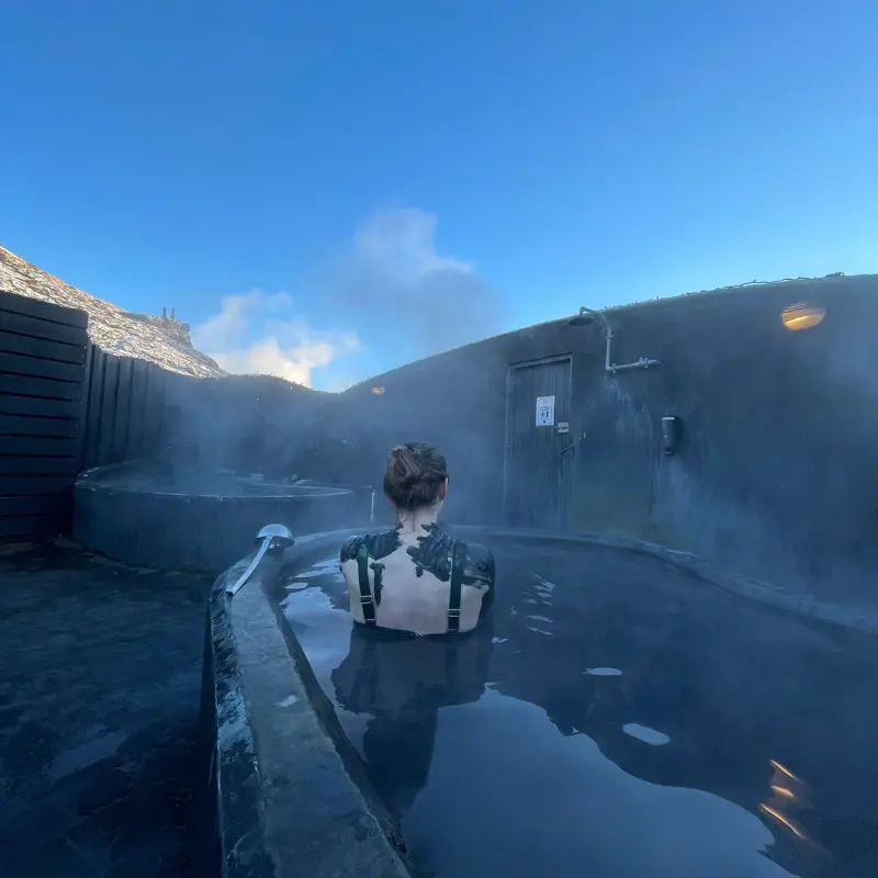 A bather in an outdoor mud pot at Hveradalir